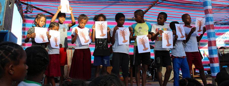 Children hold images of lobsters during an educational activity in Madagascar