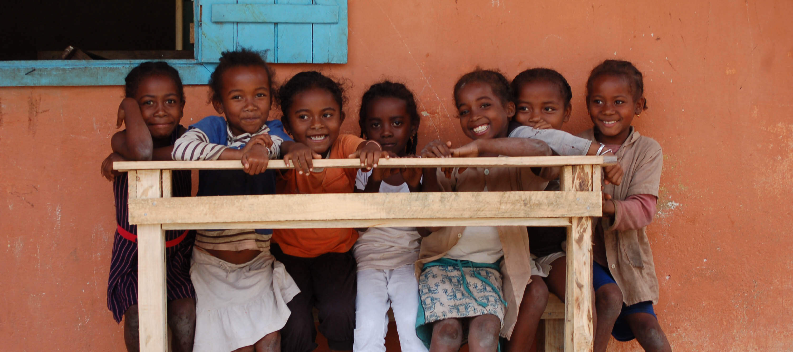 Photo of laughing children carrying a newly-finished bench to school