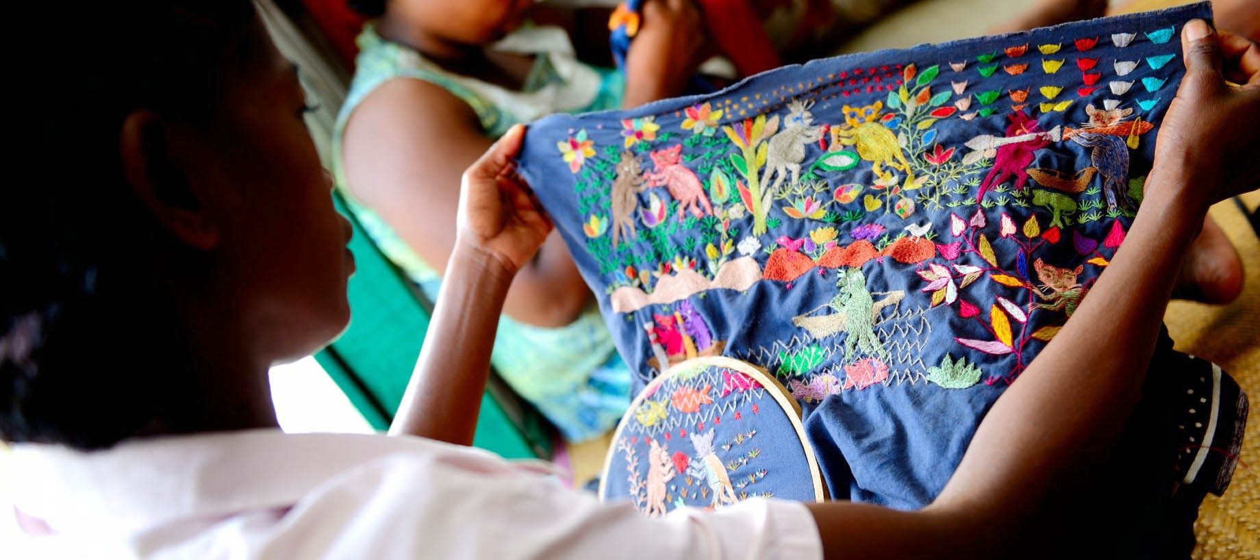 A woman looks at a colourful embroidered cushion cover