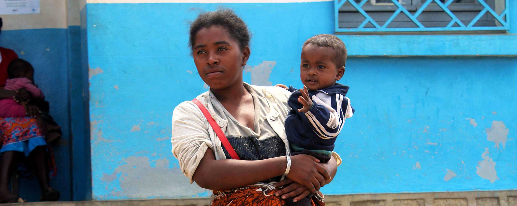 A Malagasy woman with her child at a food distribution centre receives rice