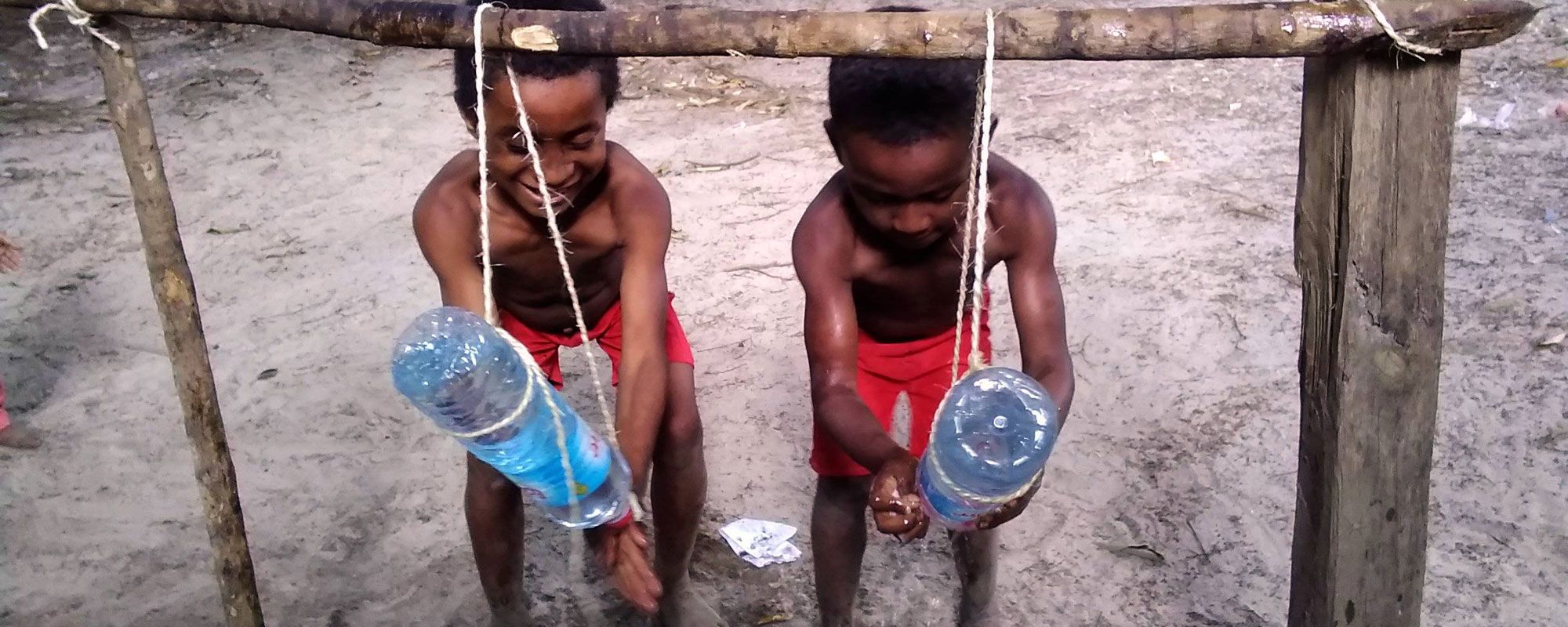 Kids using tippy taps to wash their hands in Anosy, Madagascar