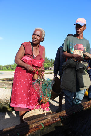  A woman holds a lobster in a bag at a landing site