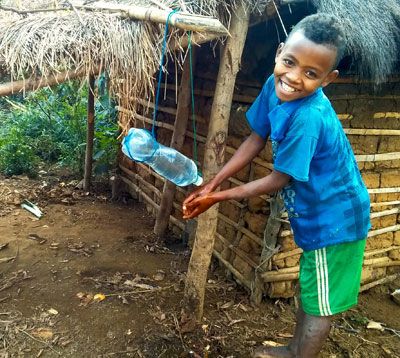  A kid smiles and washes his hands at a handwashing station