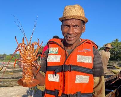 The President of Sainte Luce Fishery smiles while holding up a lobster