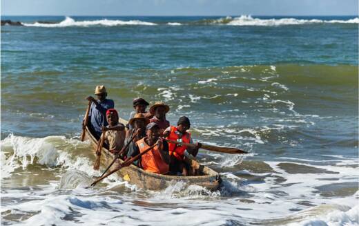 Fishers in a wooden pirogue battling the sea waves