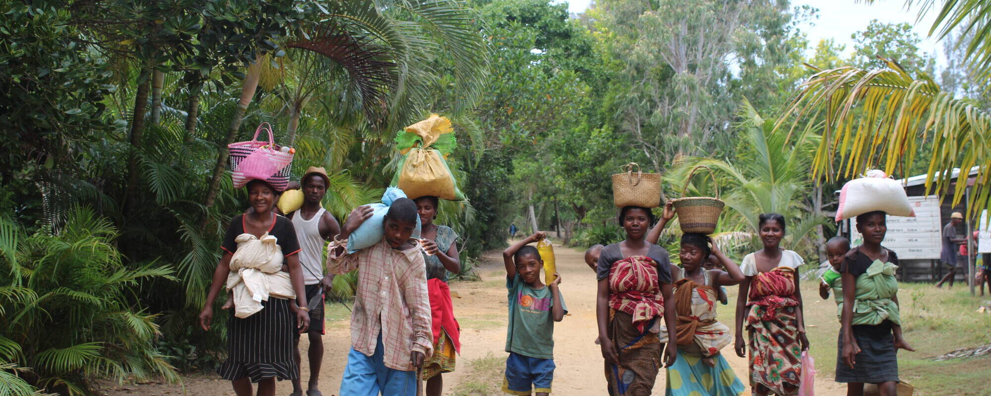 Malagasy people walking and carrying staple food stocks